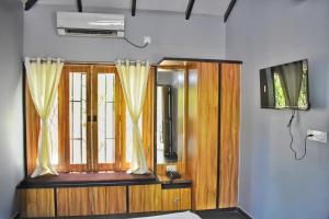 um quarto com uma televisão e uma janela com cortinas em Raghunandan Resort em Nashik