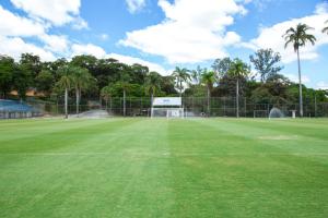 una pista de tenis con palmeras y una valla en Sesc Venda Nova, en Belo Horizonte