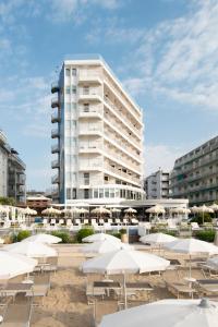 um grande edifício branco com mesas e guarda-sóis em Hotel Delle Nazioni em Lido di Jesolo