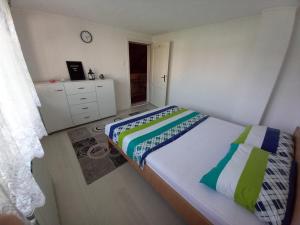 ein Schlafzimmer mit einem Bett und eine Kommode mit einer Uhr in der Unterkunft Apartment Maida in Dubrave Gornje