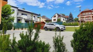 une voiture blanche garée sur un parking avec des maisons dans l'établissement Apartmanház King, à Hévíz