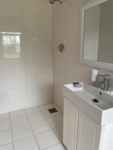 La salle de bains blanche est pourvue d'un lavabo et d'un miroir. dans l'établissement Kerry Country House, 