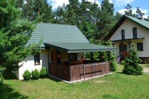 een huis met een groen dak en een hek bij Domek w Sajenku in Augustów