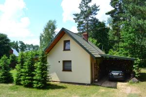 een klein wit huis met een auto voor de deur bij Domek w Sajenku in Augustów