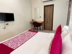 a bedroom with a bed with pink pillows and a desk at HOTEL TNCS - Couple Friendly Local IDs Accepted in Noida