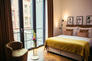 een slaapkamer met een bed, een stoel en een raam bij The Weinmeister Berlin-Mitte - Adults Only in Berlijn