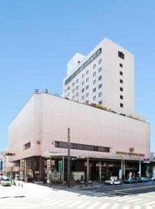 een groot wit gebouw met auto's geparkeerd voor het bij Koriyama View Hotel Annex in Koriyama