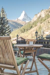 a picnic table with two chairs and a snow covered mountain at Antares Hotel in Zermatt