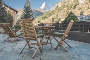 two chairs and a table on a patio with a mountain at Antares Hotel in Zermatt