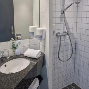 La salle de bains est pourvue d'un lavabo et d'une douche. dans l'établissement Huset Middelfart, à Middelfart