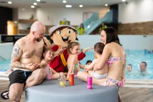 grupa ludzi siedzących obok basenu w obiekcie Atrium Hotel - Family friendly w mieście Nový Smokovec