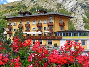 ein Hotel in den Bergen mit Blumen im Vordergrund in der Unterkunft Le Miramonti Hotel Restaurant & Wellness in La Thuile