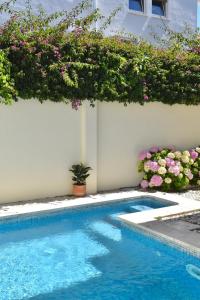 una piscina con fiori sul lato di un edificio di Beach house upscale villa with pool a Costa da Caparica