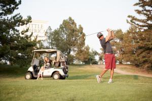 un homme balançant un club de golf sur un parcours de golf dans l'établissement Little America Hotel & Resort Cheyenne, à Cheyenne