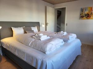 een groot bed met witte lakens en handdoeken erop bij City Harbour House in Sønderborg