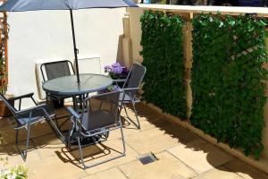 una mesa y sillas con una sombrilla en el patio en Beautifully appointed, period seaside apartment, en Folkestone