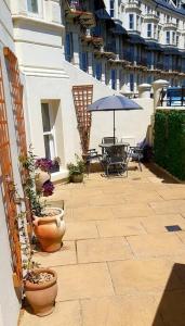 un patio al aire libre con mesa y sombrilla en Beautifully appointed, period seaside apartment, en Folkestone