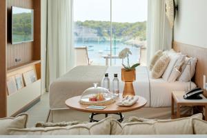 um quarto de hotel com duas camas e uma mesa com uma tigela de fruta em Meliá Cala Galdana em Cala Galdana