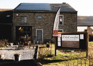 a sign in front of a house with a building with a solar roof at Il était une fois in Herbeumont