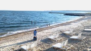 a person standing on a beach with chairs and the ocean at Falmouth Tides in Falmouth