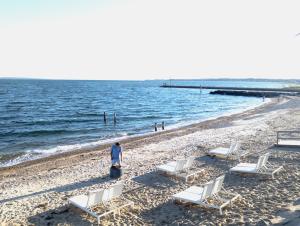 a woman standing on a beach with chairs and the ocean at Falmouth Tides in Falmouth