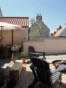 un patio con 2 sillas, una mesa y una sombrilla en The Dundonald Guesthouse & Cottage, en Culross