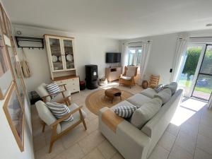 ein Wohnzimmer mit einem weißen Sofa und Stühlen in der Unterkunft Charlie & Chloé’s beachcondo ***** in De Haan