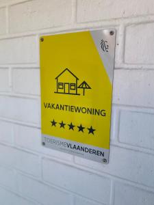 ein gelbes Warnschild an einer Ziegelmauer in der Unterkunft Charlie & Chloé’s beachcondo ***** in De Haan