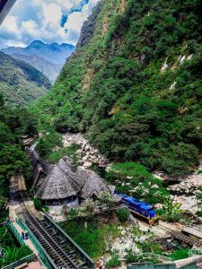 un train sur des pistes à côté d'une montagne dans l'établissement Machupicchu Adventure Hotel, à Machu Picchu