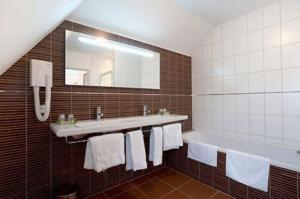 bagno con vasca, lavandino e specchio di Hostellerie St Vincent a Nuits-Saint-Georges