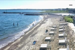 a beach with chaise lounges and the ocean at Falmouth Tides in Falmouth