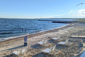 a person standing on a beach with chairs and the ocean at Falmouth Tides in Falmouth