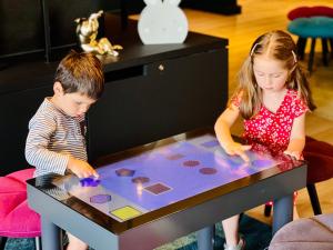 un garçon et une fille jouant à une table dans l'établissement Novotel Dijon Sud, à Dijon