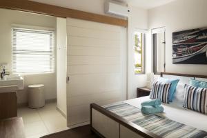 a bedroom with a bed and a sink and a bathroom at Cap Ouest by Horizon Holidays in Flic-en-Flac