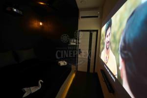 a person watching a movie on a television screen at Hotel Cineplex in Coimbatore