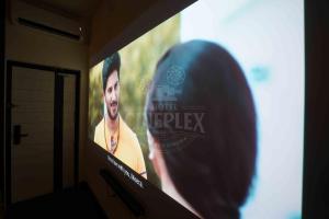 a large screen with a sign on a wall at Hotel Cineplex in Coimbatore