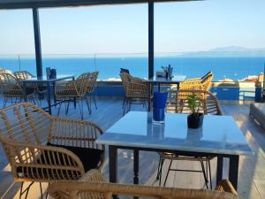 un patio con tavoli, sedie e vista sull'oceano di Blue View Apartments a Kavala