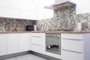 a kitchen with white cabinets and a stove top oven at Maison 3 chambres proximité aéroport et grand axes in Charleroi