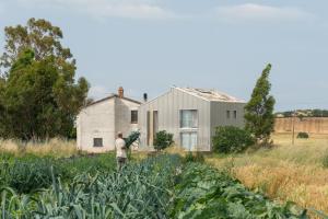 un hombre parado en un campo frente a una casa en Anonima Agricola, en Orbetello