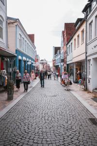 um grupo de pessoas andando por uma rua de paralelepípedos em Altes Töpferhaus em Husum