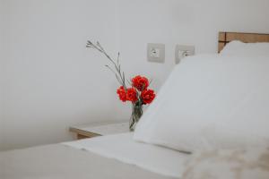 een vaas met rode bloemen op een bed bij Panoramic Vlachos in Gjirokastër