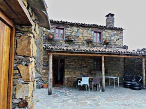 een stenen huis met een tafel en stoelen buiten bij Casa Princesa Peralta in Lousã