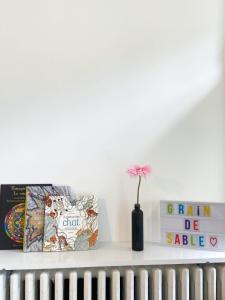 une étagère avec des livres et une fleur dans un vase dans l'établissement Le Grain de Sable, à Thionville