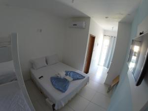 a small white room with a bed in it at Xodó do Peró Suítes in Cabo Frio