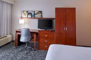 una camera d'albergo con scrivania, TV e letto di Sonesta Select Indianapolis Carmel a Carmel