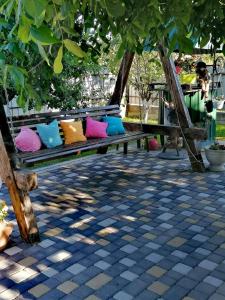 a bench with colorful pillows sitting under a tree at Садиба Герасімових in Kamianets-Podilskyi