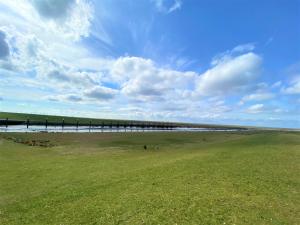 een pier op het strand met een grasveld bij Appartement 1 mit Küche und neuem Bad, frisch saniert in Friedrichskoog