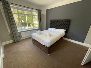 a bedroom with a bed with white sheets and a window at Bayside GuestHouse in Bournemouth