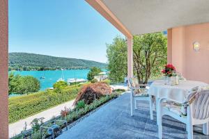 stół i krzesła na patio z widokiem na wodę w obiekcie Appartements Schwarzvilla w mieście Velden am Wörthersee