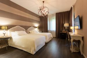 ein Hotelzimmer mit 2 Betten und einem Schreibtisch in der Unterkunft Like Home Boutique Hotel in Azzano San Paolo